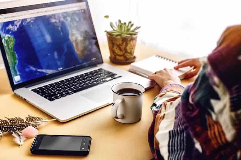 Staying Connected While Working Remotely 1 concept photo of someone working from home, sitting in front of a desk, drinking a cup of coffee ready to make some notes on their pad.